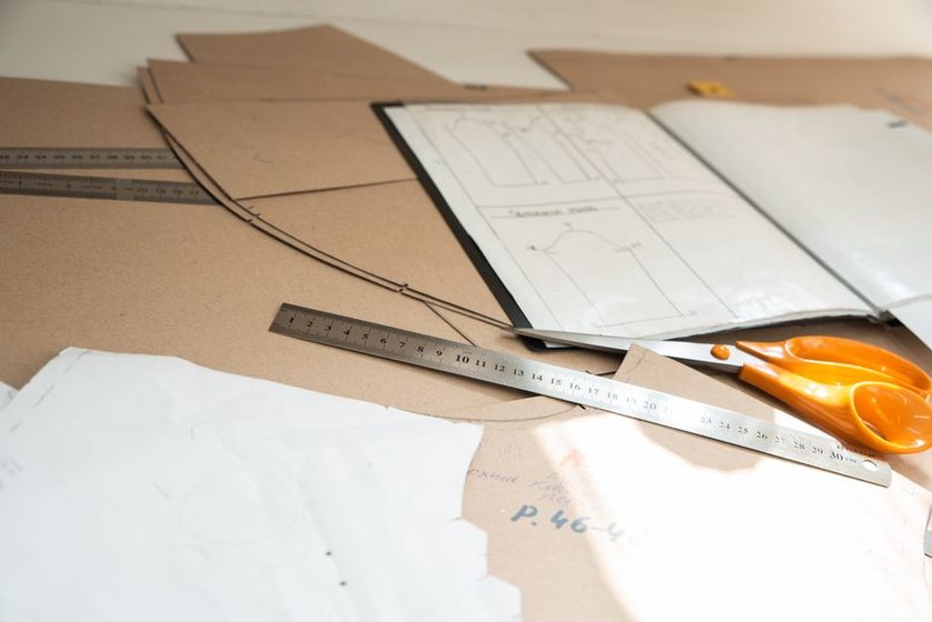 A drafting table with rulers, a pattern block, and hand-written measurement notes