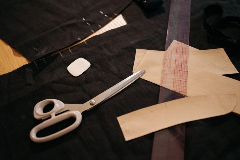Pattern paper pieces laid out on a cutting table with a tape measure and tracing wheel